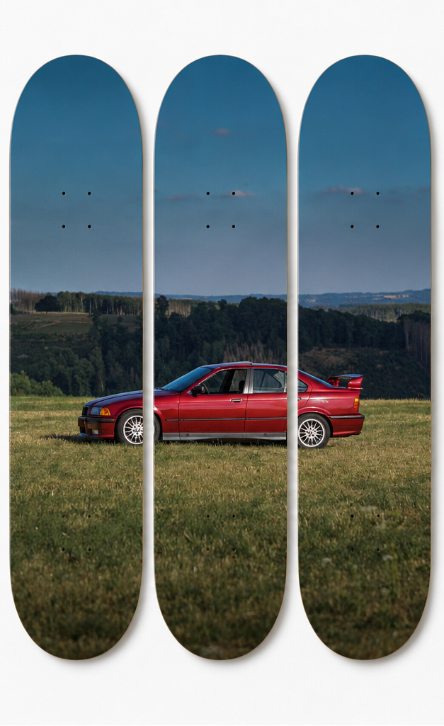 Skateboard decks with a red E36 sports car on a grassy field with blue skies. 