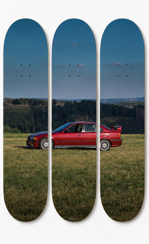 Skateboard decks with a red E36 sports car on a grassy field with blue skies. 