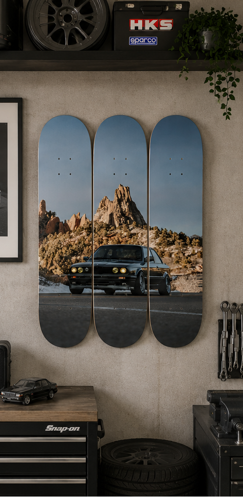 Skateboard decks with a desert landscape and car design, displayed on a wall