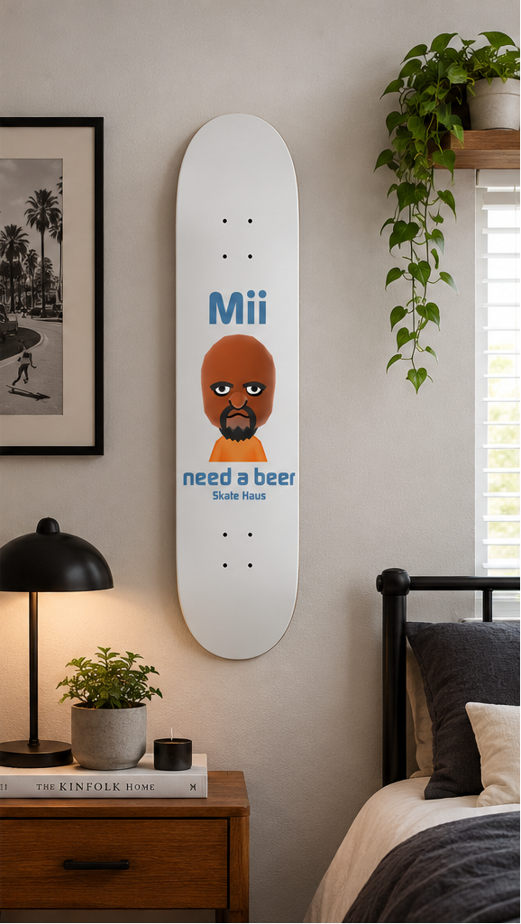 Three views of a white skateboard deck featuring a cartoon character with an orange bald head and beard, wearing an orange shirt, with blue text reading 'Mii need a beer Skateboard'. The left two views show the deck against a plain white background, and the right view shows the deck mounted on a bedroom wall.