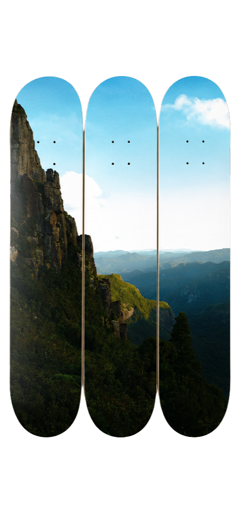 Three skateboard decks with mountain and sky design on a white background